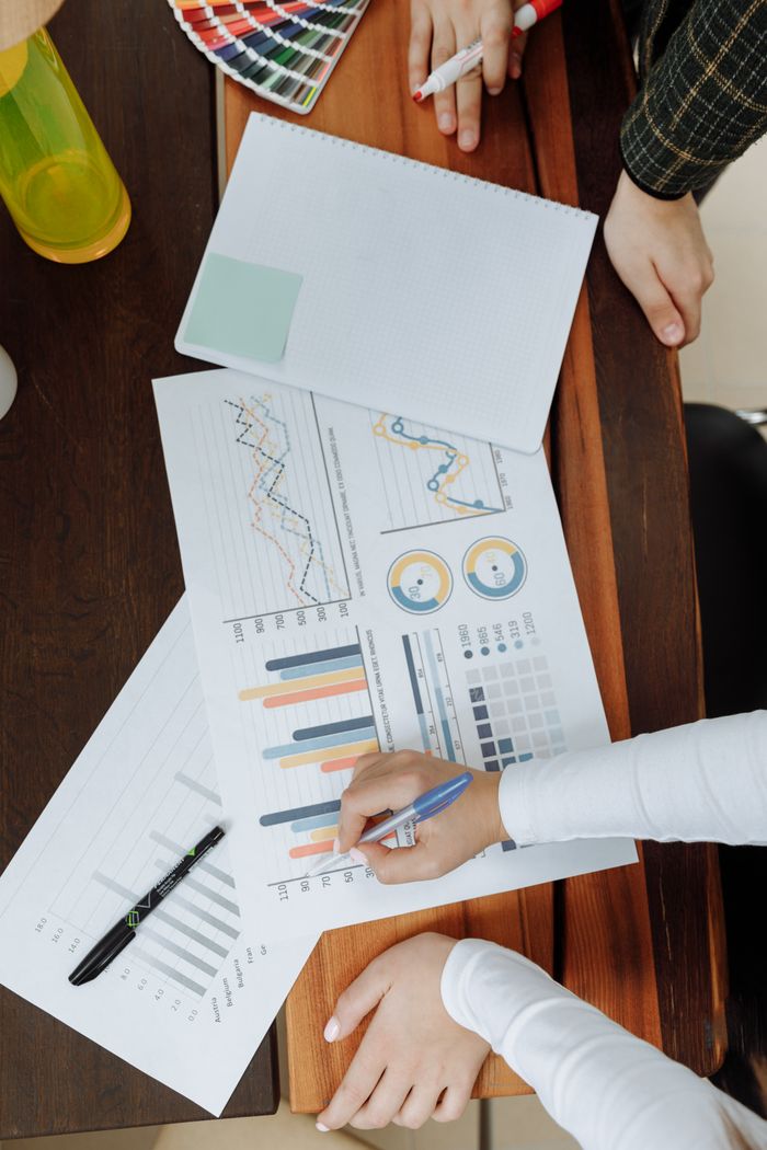 why-choose-us Top view of business team analyzing charts and data on paper for strategic planning.