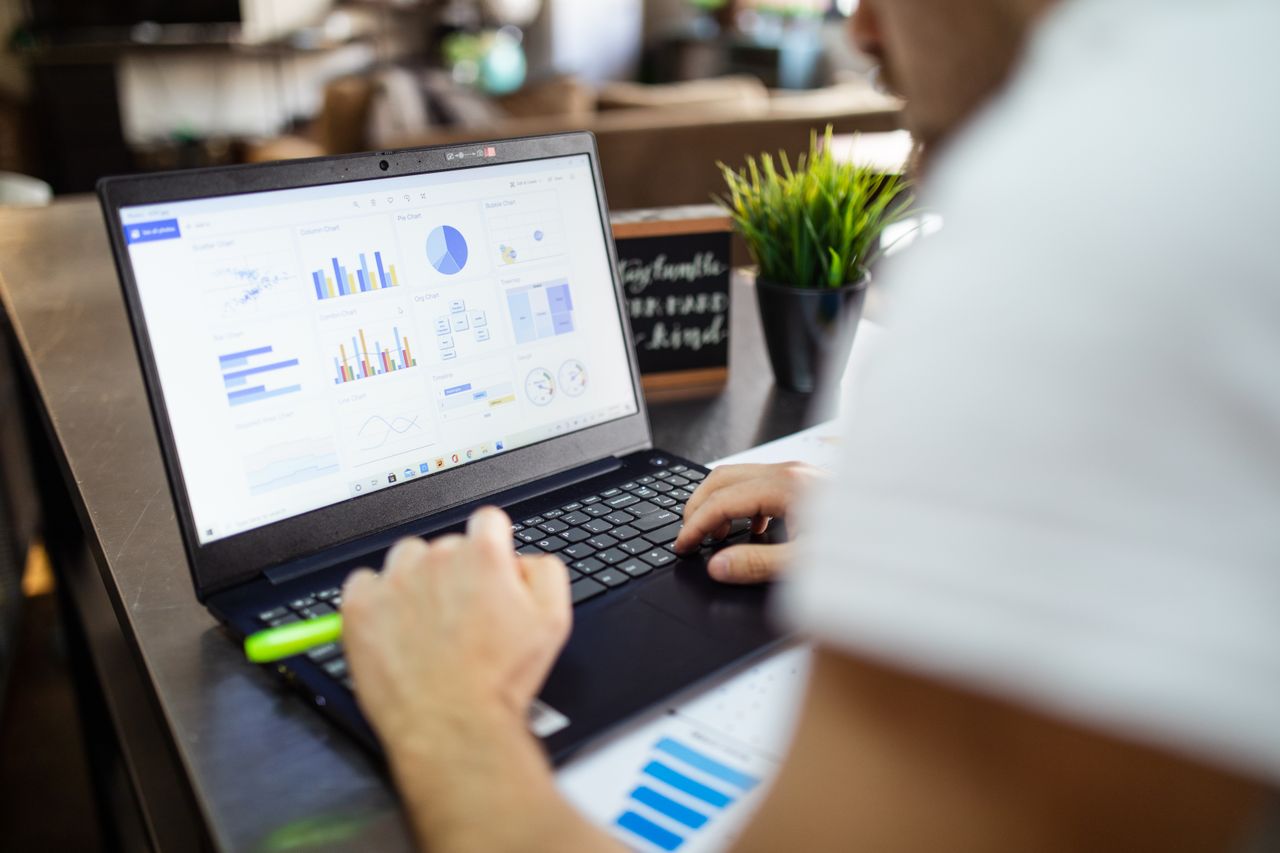 services-03 Focused business analysis with charts and graphs on a laptop in a modern office setting.